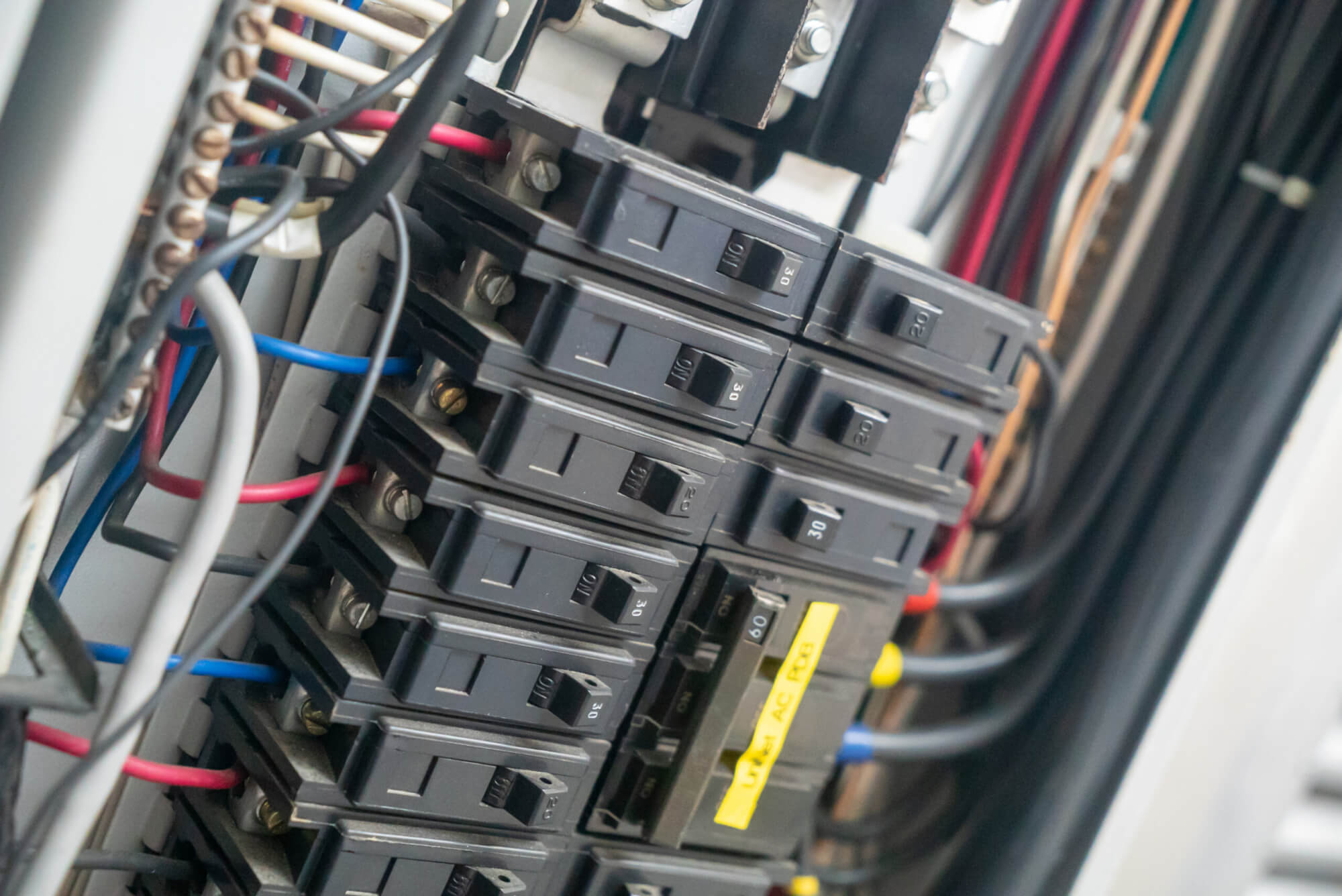 Close-up of an electric circuit breaker panel showcasing various circuit breakers, wiring, and connections essential for electrical safety and power management.