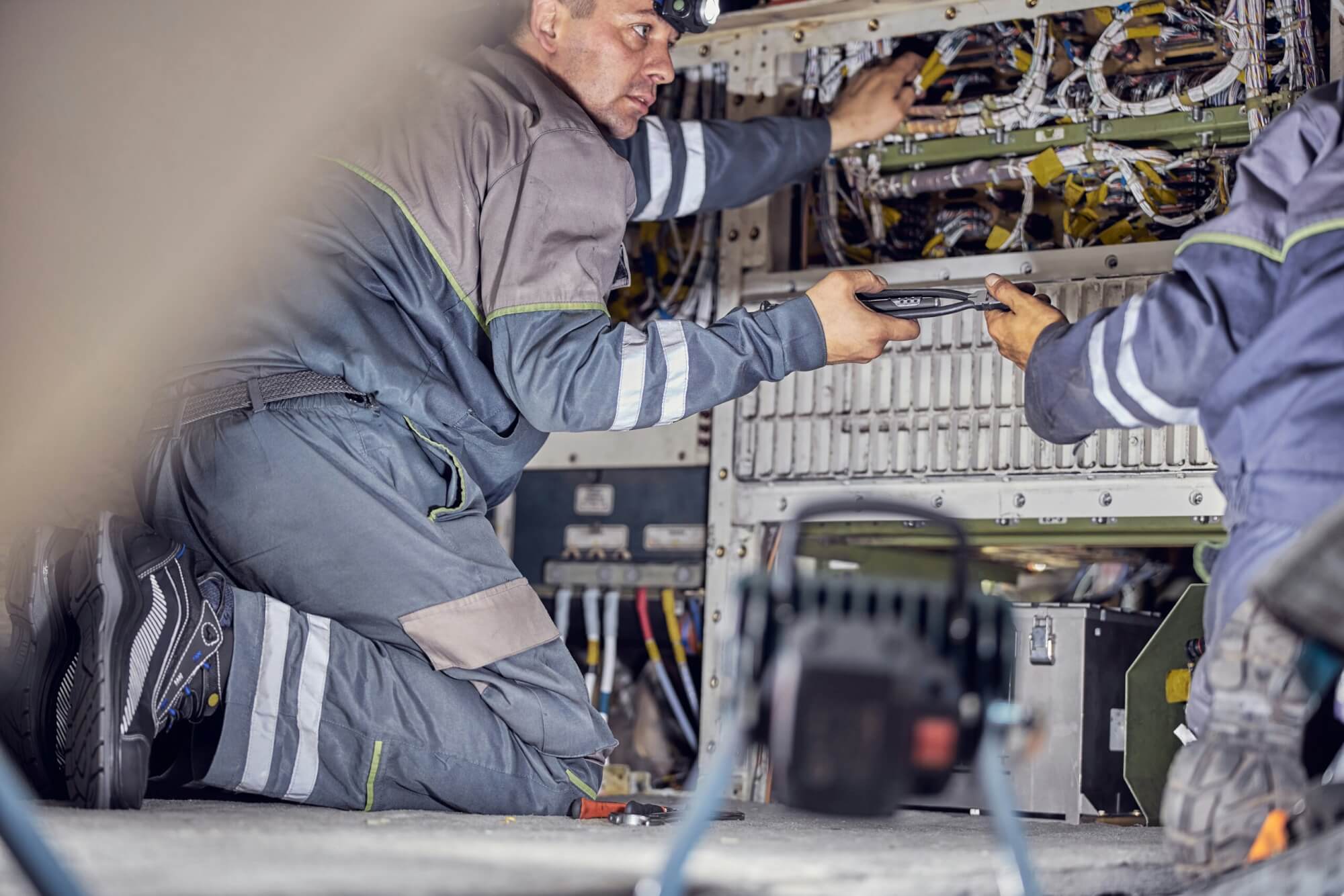 Two people working on an electrical circuit breaker or some other type of electrical infrastructure.