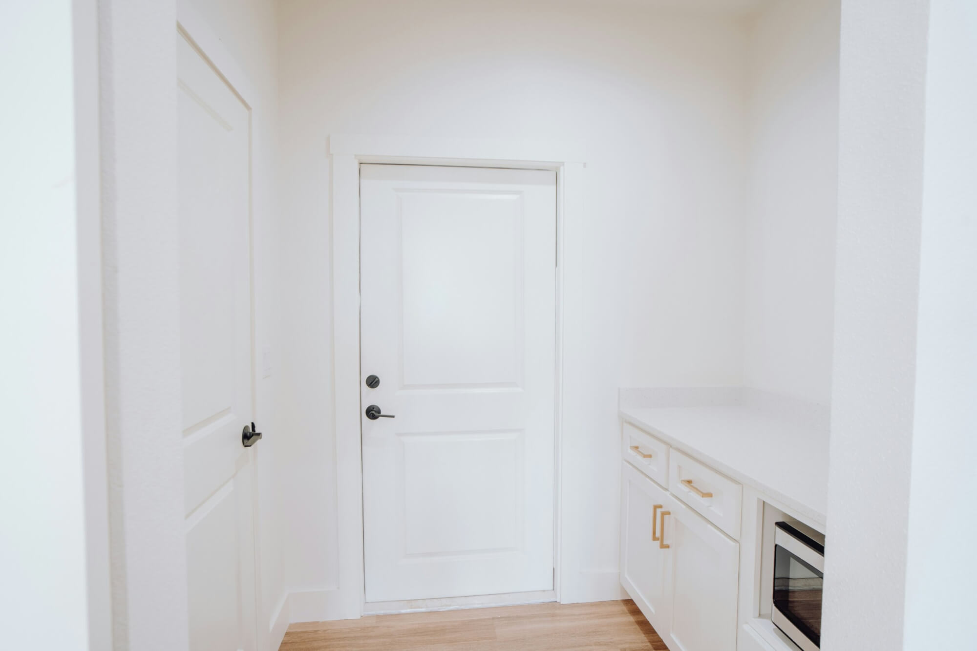 A photo of the inside of a house that shows a white interior door leading to another room within the house.