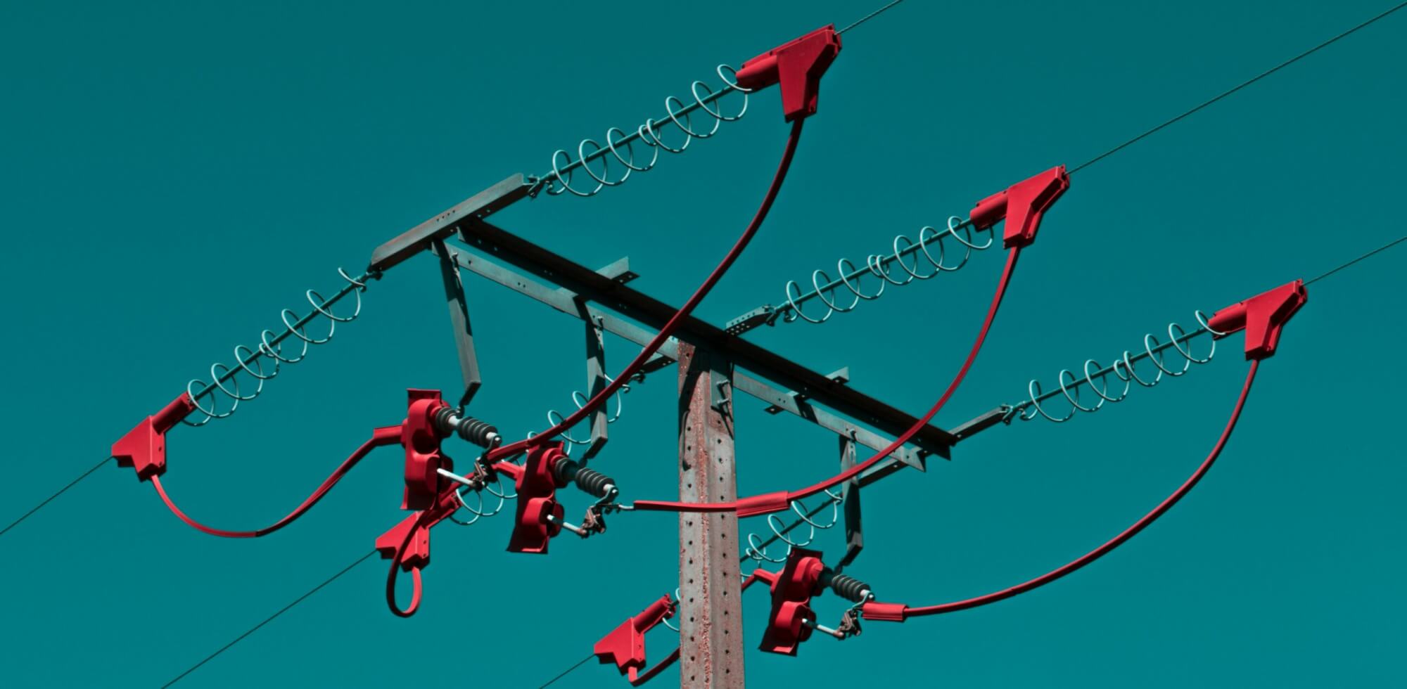 A picture of a blue sky with an electrical grid and stand off insulator.