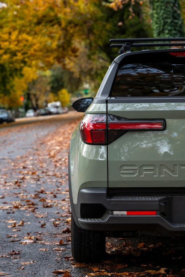 A Santa Cruz truck in the fall on a street that has leaves that have fallen around it.