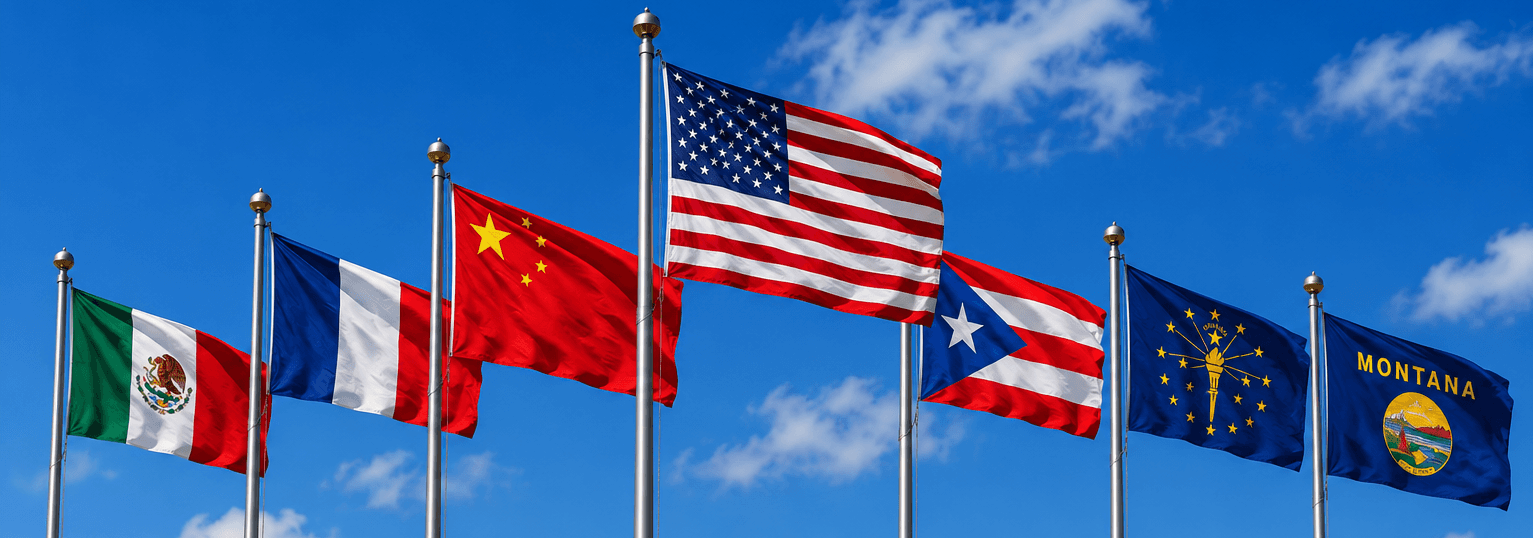 A picture of a Mexico Flag, France Flag, China Flag, United States Flag, Puerto Rico Flag, Indiana Flag, and Montana Flag blowing in the breeze with a blue sky in the background.