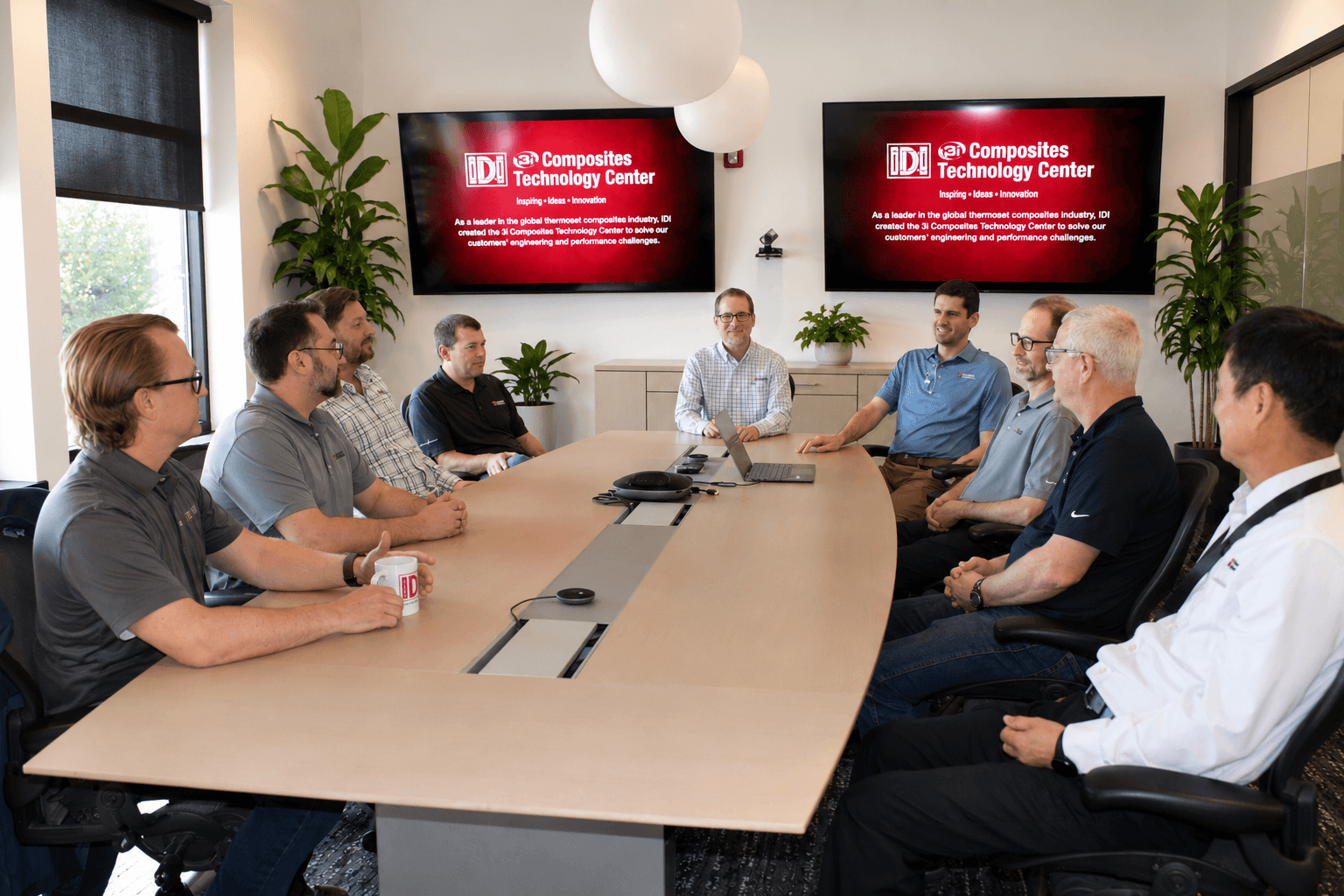 A group of people talking around a conference table with a presentation on the screen