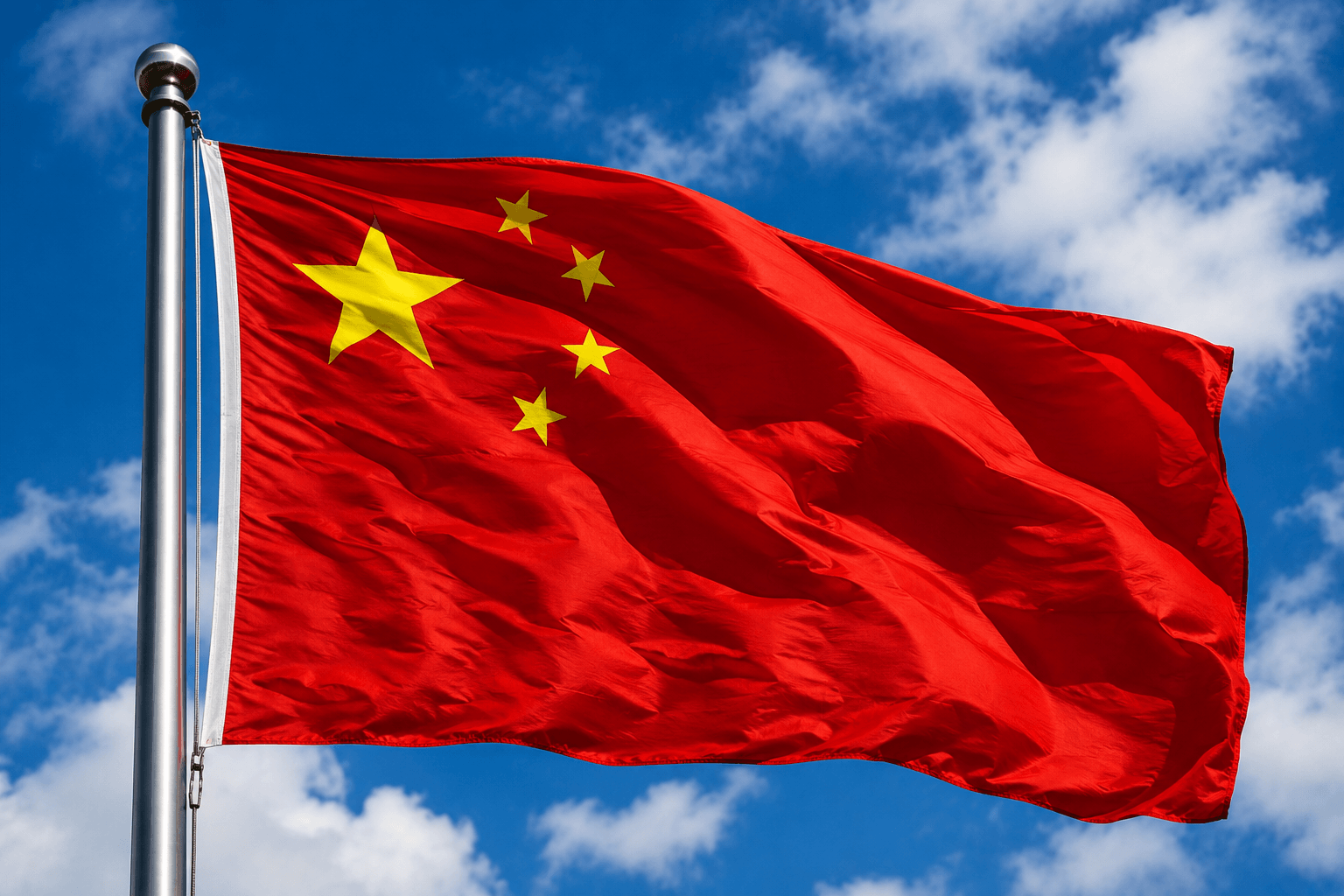 A picture of the Chinese flag blowing in the wind with a blue sky background.