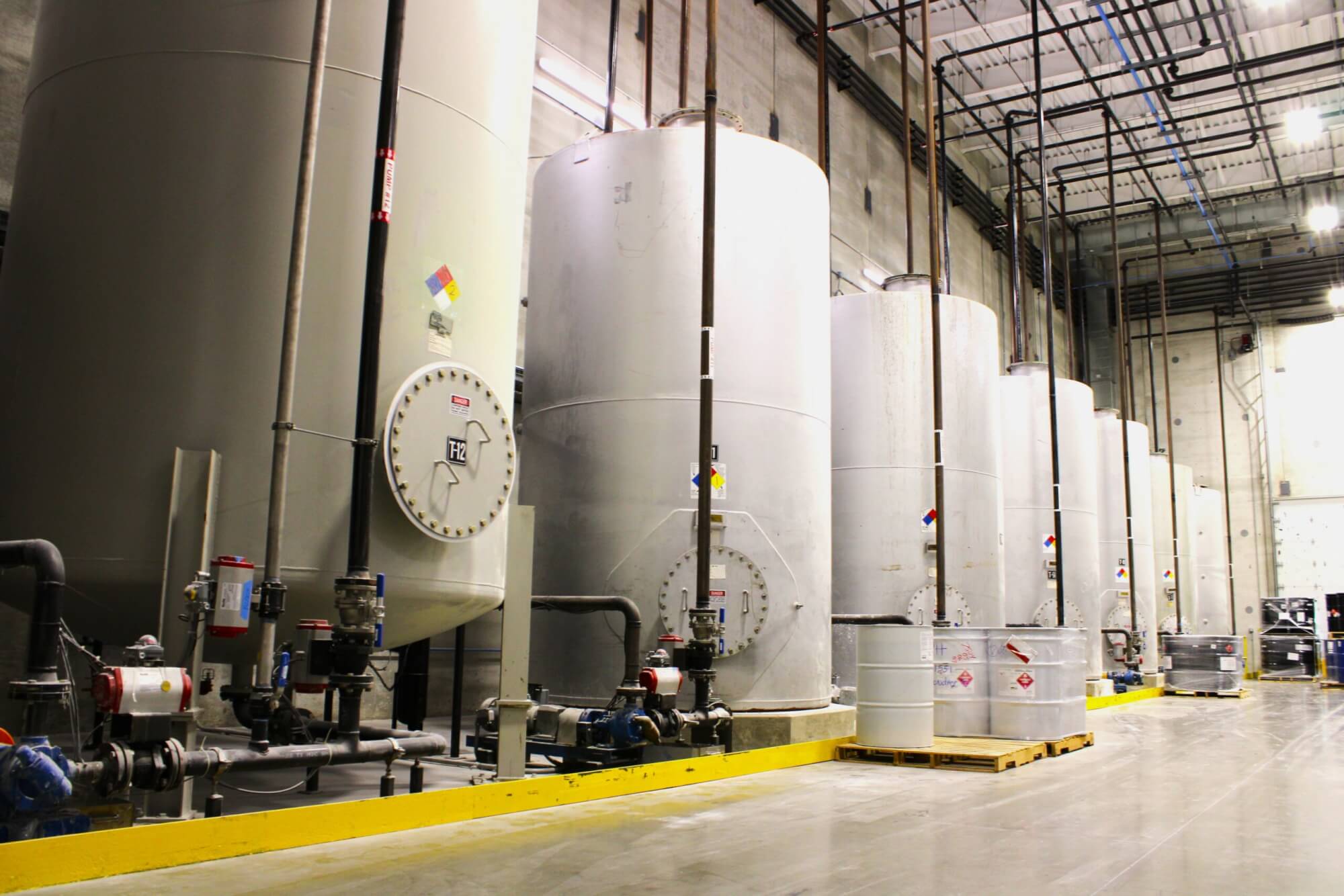 A picture of a seven large resin tanks in a manufacturing facility.