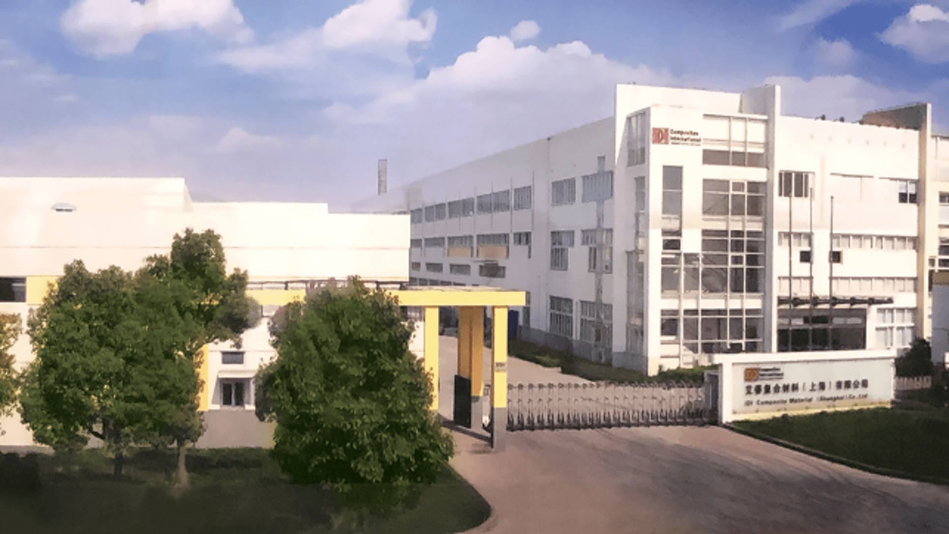 A picture of a manufacturing plant in an area of China with a blue sky and clouds in the background and green trees in the forefront.