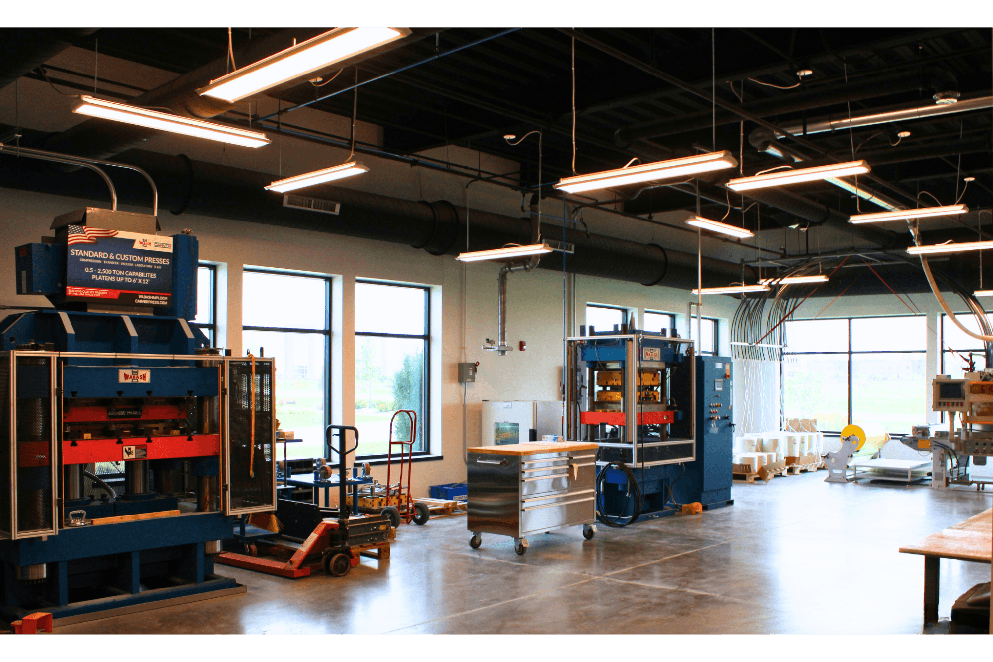 A wide angle picture of two different presses that are on a manufacturing grey concrete floor.