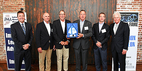 A picture of six people standing side by side with an award that was given by Indiana Manufacturers' Association to IDI Composites International.